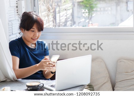Young female holding smartphone and reading content in social network while sitting in cafe. Copy space. Selective focus.