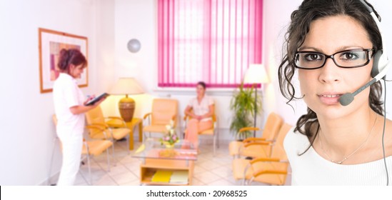 Young Female Hospital Receptionist Receiving Phone Calls In Headset With Clinic Waiting Room In Background.