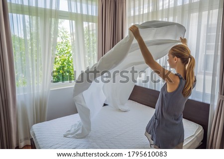 Young Female Housekeeper Changing Bedding In Hotel Room