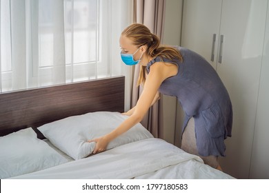 Young Female Housekeeper Wearing A Medical Mask Due To Coronavirus Quarantine COVID 19 Changing Bedding In Hotel Room