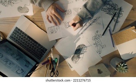 Young female illustrator drawing pencil sketches on paper. Drawings on the sheet of papers in front of her. Illustration animation, storyboard, video game film production, animation design studio. - Shutterstock ID 2211276715