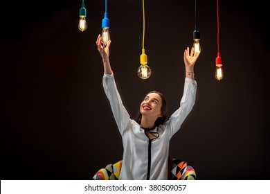 Young Female Inventor Touching Illuminated Retro Lamp On The Dark Background