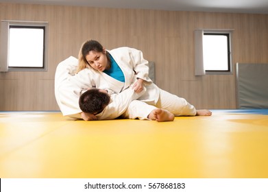 Young female judoka holding stronger male opponent