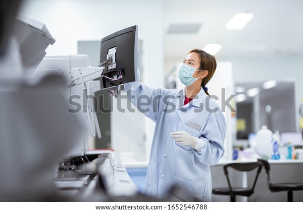 young female laboratory\
technician working with automation blood  analyzer in medical\
laboratory