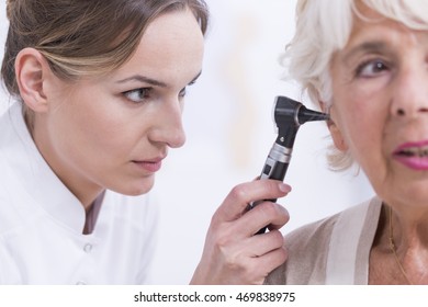 Young female laryngologist checking senior patient's ears - Powered by Shutterstock