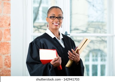Young female lawyer working in her office with a typical law book and a file or dossier