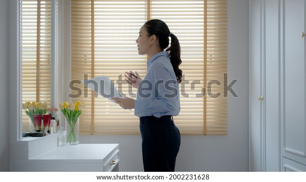 Young female leader, asia people lady or mba\
student happy standing smile look at in front of mirror pep talk\
for sale pitch hold paper document script public speak skill for\
job career self improve.