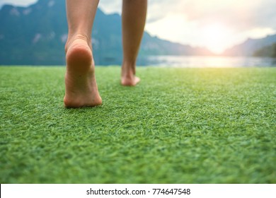 Молодые женские ноги ходьба к закату на земле травы с размытие горы и озера