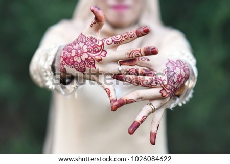 young female malaysian bride showing her wedding ring with hand painted with henna