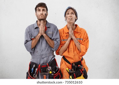 Young Female And Male Plumbers Keep Hand As Pray For Rest Or Holidays, Being Exhausted After Hard Work, Isolated White Background. Dirty Maintenance Worker Keep Palms Together, Look Hopefully