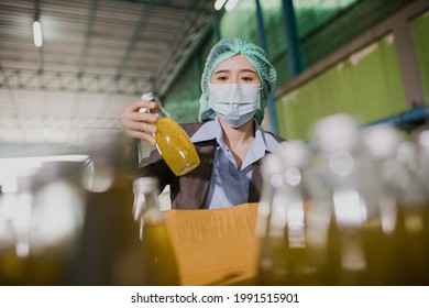 Young female manager factory checking juice bottles before shipment. Inspection quality control. Manager  inspecting production line at drinks production factory