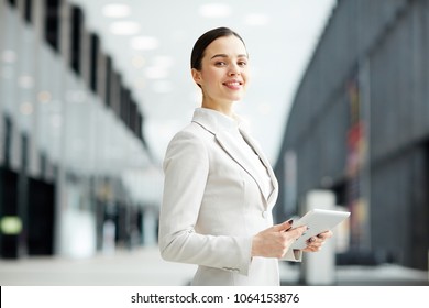 Young female manager with touchpad standing in the middle of airport lounge while looking for some information in the net - Powered by Shutterstock