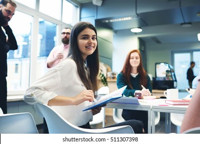 Young Female Manager Writes Important Point Of Reference In Time To The Project Meeting With Colleagues. Attractive Girl Trainee Keeps Records For Mastering New Skills From The Experts During Briefing