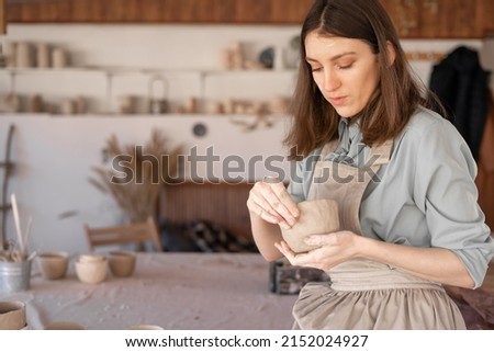 Similar – Image, Stock Photo Young female sitting by table and making clay or ceramic mug