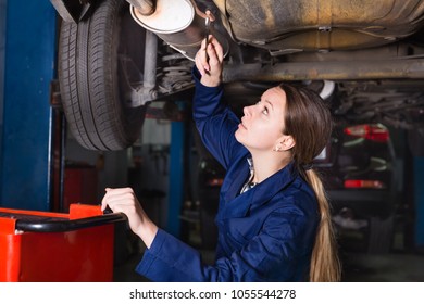 Young female master is repairing car on her workplace in workshop 