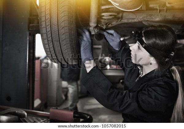 Young female master is repairing car on her\
workplace at workshop