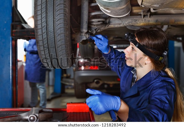 Young female master is repairing car on her workplace at\
the workshop 