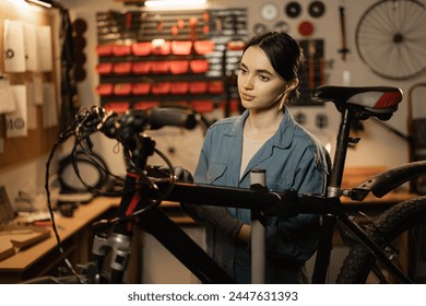 Young female mechanic repairing bike in workshop or garage. Bike workshop interior. Copy space - Powered by Shutterstock