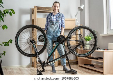 Young female mechanic is standing next to a bicycle that is about to be disassembled for maintenance. Concept of repairing and preparing the bike for the new season