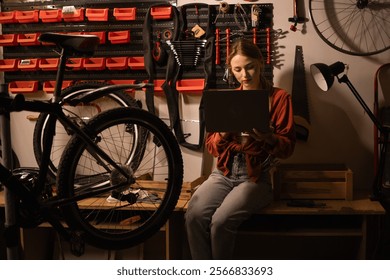 Young female mechanic using laptop working in garage or bike workshop. Female bicycle Mechanic. Copy space - Powered by Shutterstock