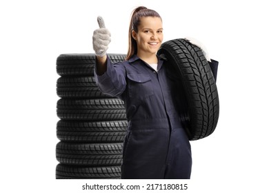 Young female mechanic worker carrying a car tire and showing thumbs up isolated on white background - Powered by Shutterstock