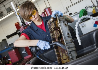 Young Female Mechanic Working With Welding Torch On Vehicle Machinery Part In Auto Repair Shop