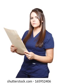 Young Female Medical Professional Wearing Dark Blue Scrubs With A Serious Expression Holding A Legal Sized Manila Folder Isolated On A White Background.