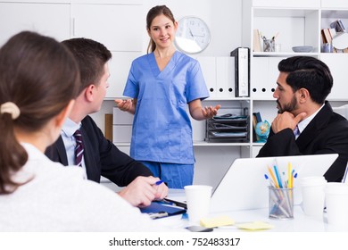 Young Female Medical Worker Telling Office Staff About First Aid