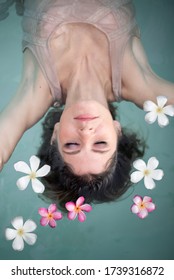 Young Female Model In Hippie, Boho Style. Woman In Swimming Pool With Flowers