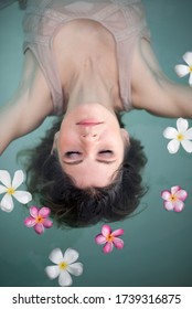 Young Female Model In Hippie, Boho Style. Woman In Swimming Pool With Flowers