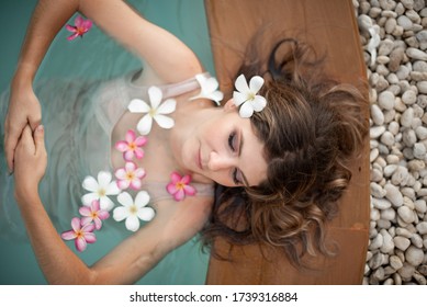 Young Female Model In Hippie, Boho Style. Woman In Swimming Pool With Flowers