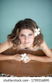 Young Female Model In Hippie, Boho Style. Woman In Swimming Pool With Flowers