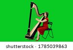 Young female musician in red dress playing harp