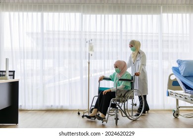 Young female muslim doctor wearing face mask pushing the wheel chair of young sick muslim pateint in hospital. - Powered by Shutterstock