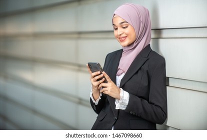 Young Female Muslim Entrepreneur Looking At Her Smartphone. Shallow Depth Of Field.