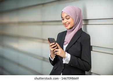 Young Female Muslim Entrepreneur Looking At Her Smartphone. Shallow Depth Of Field.