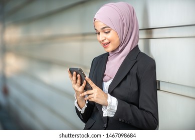 Young Female Muslim Entrepreneur Looking At Her Smartphone. Shallow Depth Of Field.