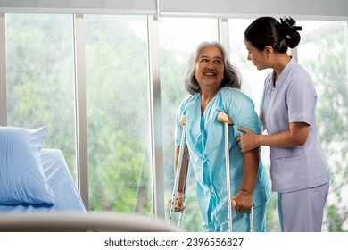 Young female nurse caregiver helping old woman patient standing holding walking cane stick at hospital, elder people care medical services concept. - Powered by Shutterstock