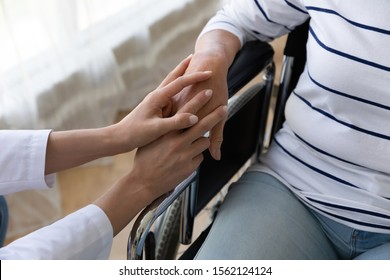 Young Female Nurse Caregiver Hold Hand Support Disabled Handicapped Senior Adult Grandma Patient Sit On Wheelchair, Old Paralyzed People With Disability Medical Help Assistance Concept, Close Up View