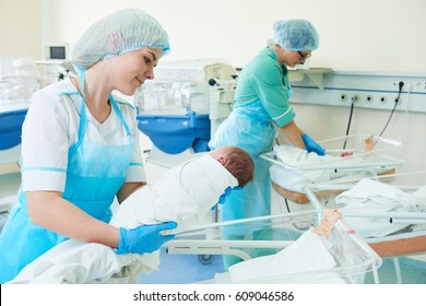 young female nurse holding a newborn baby in hospital