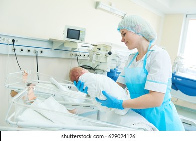 young female nurse holding a newborn baby in hospital