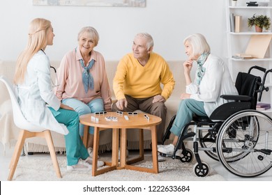 Young Female Nurse Playing Domino With Senior Patients