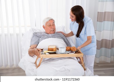 Young Female Nurse Serving Food To Senior Male Patient