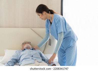 Young Female Nurse Taking Care Senior Man To Bed In The Room At Hospital Ward. Asian Female Nurse Caring Elderly Man Patient In Room At Nursing Home. Hospital Care And Older Adults Concept