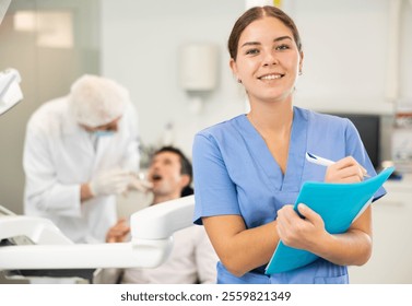 Young female nurse taking notes during examination of patient in dental office - Powered by Shutterstock