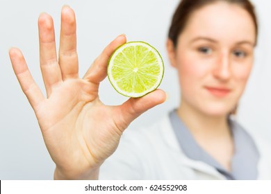 Young female nutritionist on white background with half citrus. Focus on lime and hand