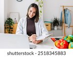 Young female nutritionist talking with patient through laptop computer video call at clinical consultation room. Healthy lifestyle, nutrition and diet concept.