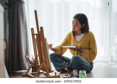 Young Female Painting On Canvas In Living Room At Home. Hobby And Leisure Concept.