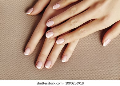 Young Female Palm on beige background. Beautiful Glamour Manicure. French Style. Nail polish. Care about Hands and Nails, clean Skin
