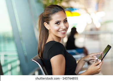 young female passenger at the airport using her tablet computer while waiting for flight - Powered by Shutterstock